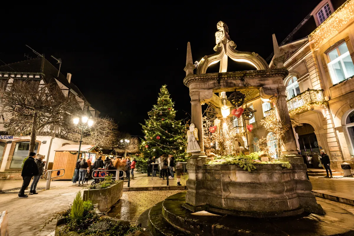 Puits de la place illuminé avec un sapin de Noël à Rosheim