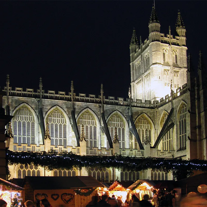 Bath Abbey at night with Christmas garlands on the market chalets