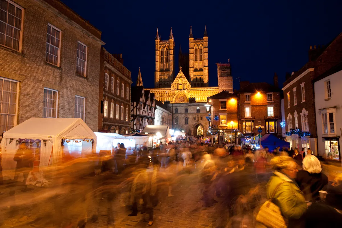 Crowds at Lincoln Christmas Market with the cathedral towers at night