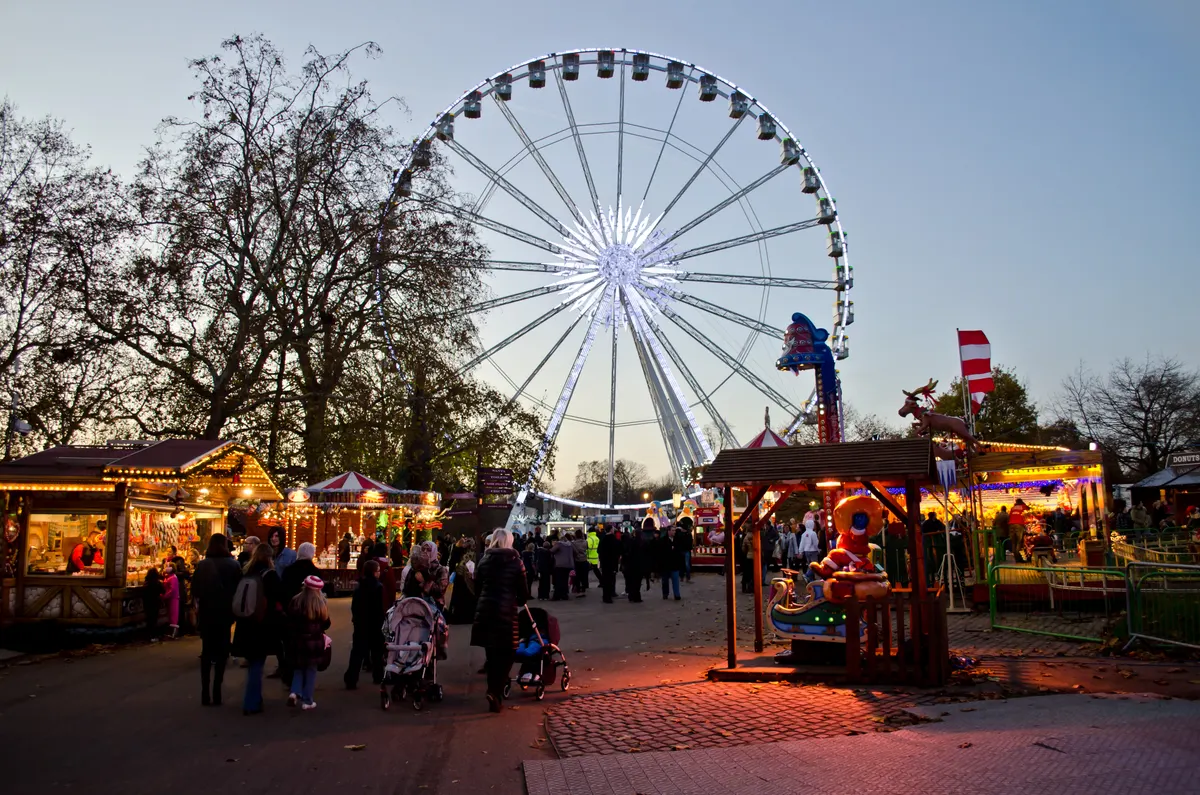 Giant wheel and festive stalls at Hyde Park Winter Wonderland at dusk
