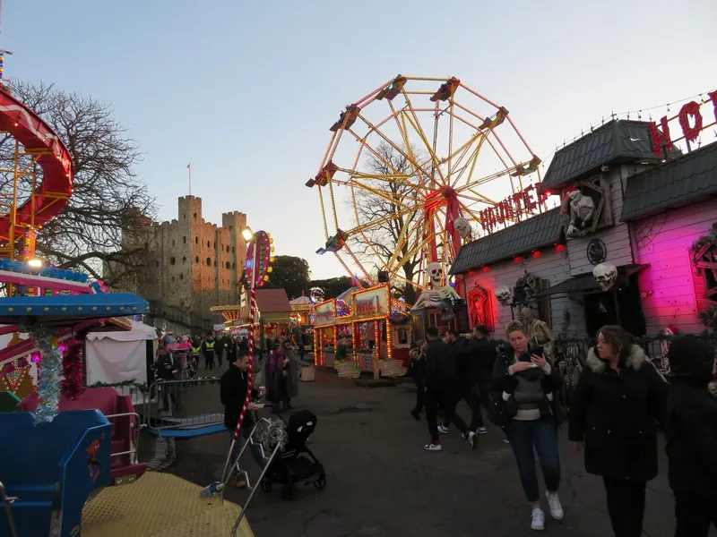 Funfair rides and stalls beneath Rochester Castle at Christmas