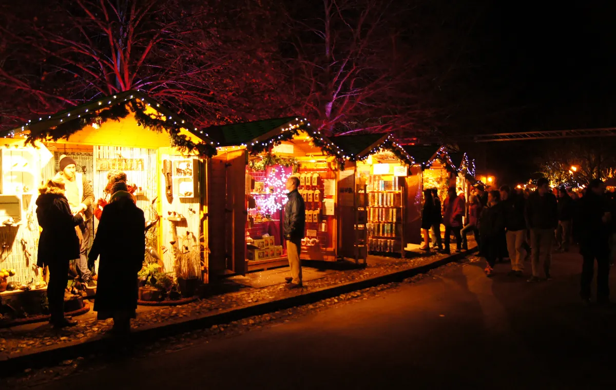 Illuminated wooden chalets at Winchester Cathedral Christmas Market at night