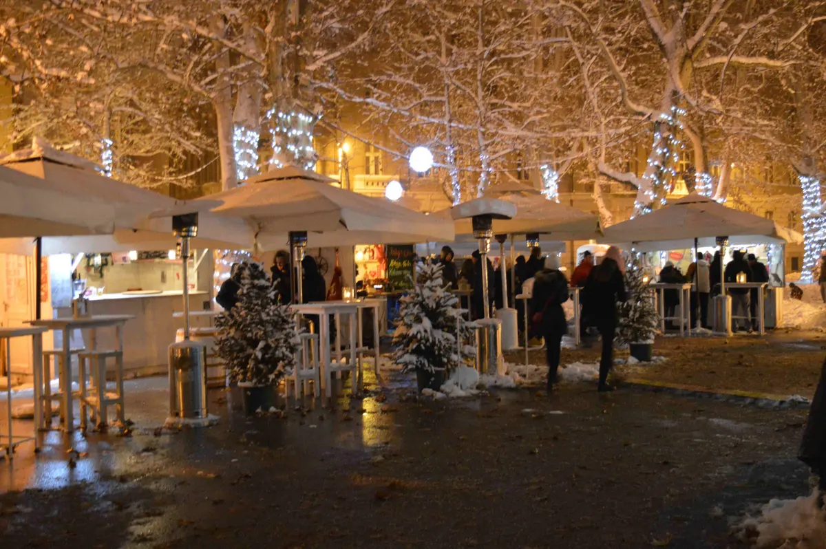 Štandovi i sjedeći kutak pod osvijetljenim platanama na Zrinjevcu u Zagrebu