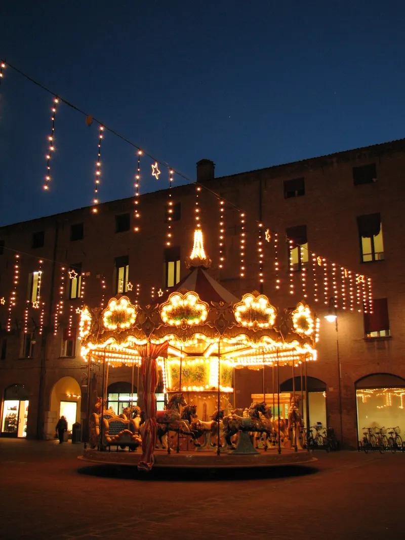 Giostra illuminata tra i palazzi del centro di Ferrara a Natale