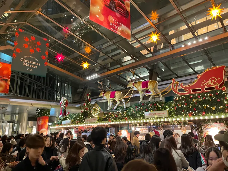 六本木ヒルズのクリスマスマーケットに並ぶ屋台とトナカイ・そりの装飾、夕方の賑わい