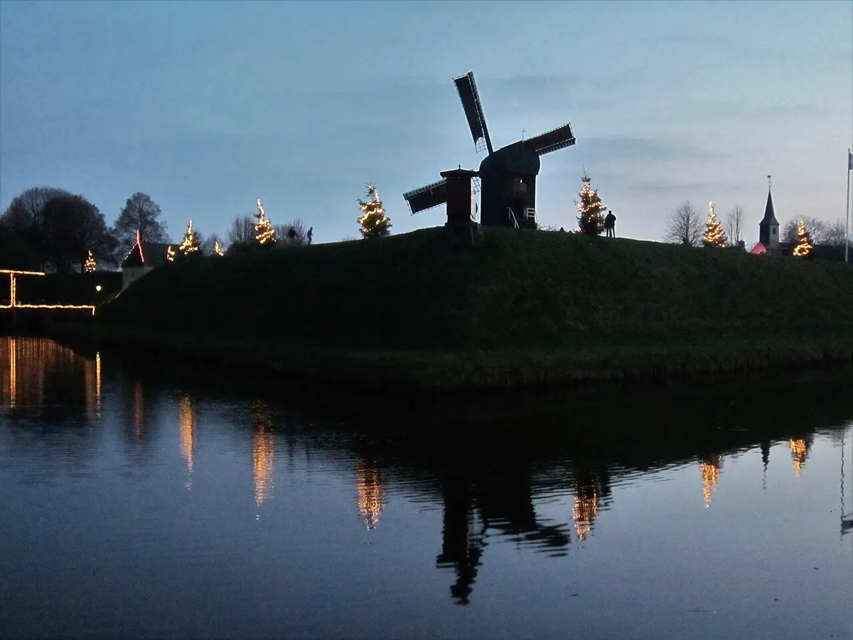 Verlichte kerstbomen op de wallen van vestingdorp Bourtange bij schemering