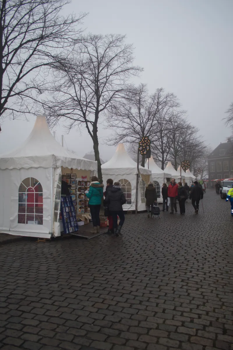 Witte kerstmarkttenten in de mist langs de haven van Dordrecht