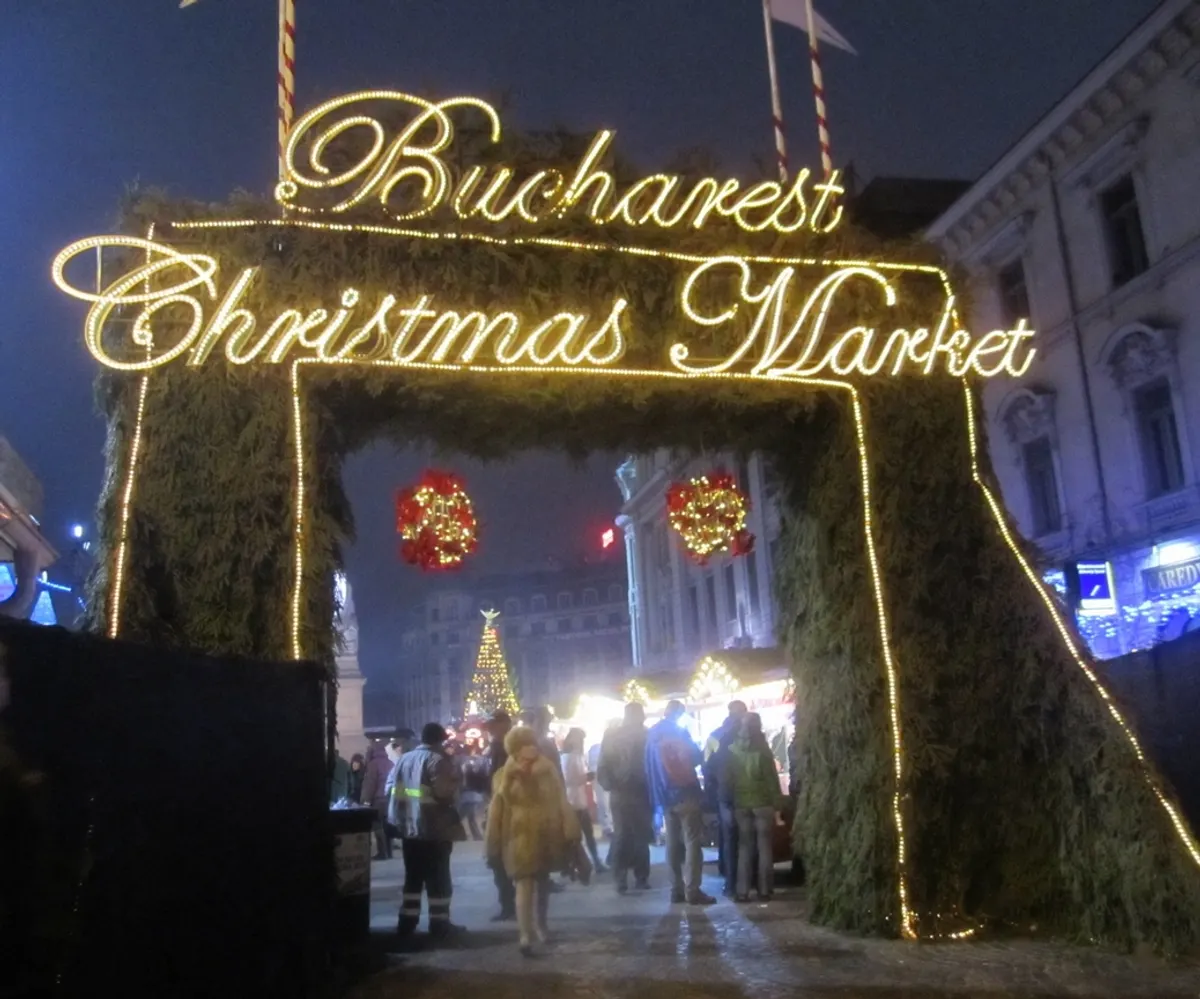 Intrarea luminată în Bucharest Christmas Market, cu poarta de brad și globuri roșii
