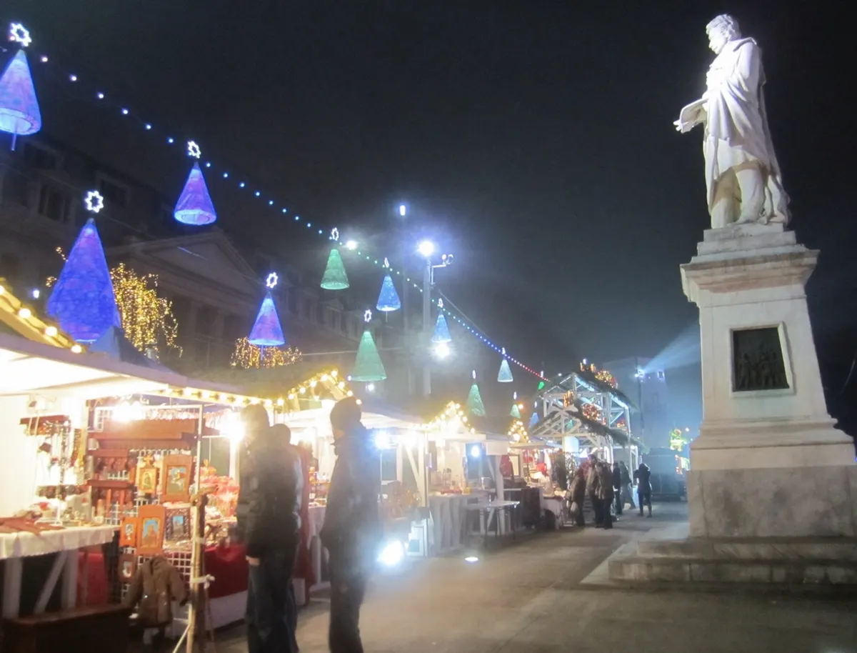 Târgul de Crăciun din Piața Universității, București, seara, cu standuri și decorațiuni luminoase
