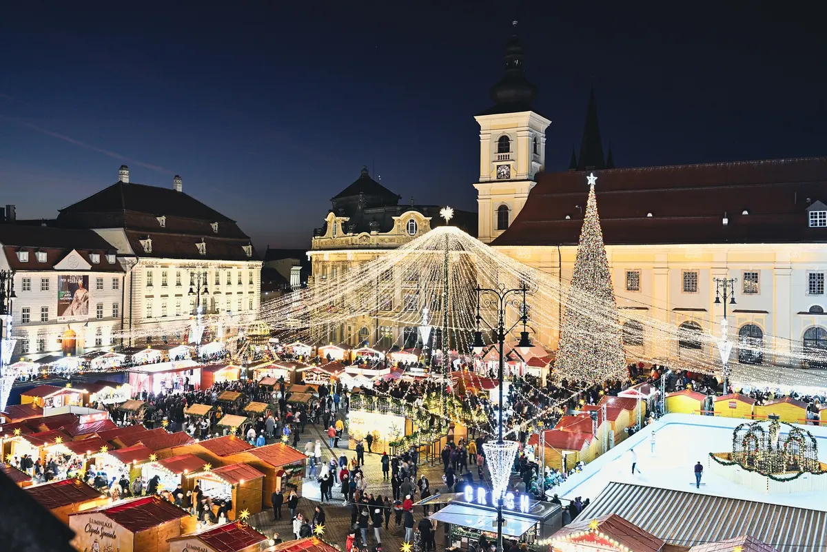 Târgul de Crăciun din Piața Mare, Sibiu, la căderea serii, cu căsuțe de lemn și bradul luminat