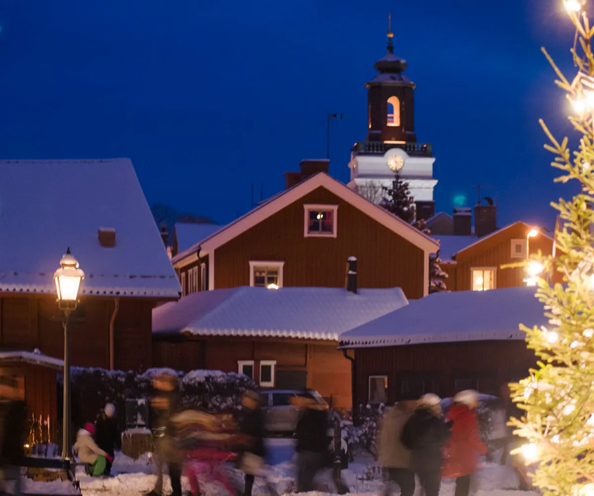 Snötäckta trähus och julgran i Eksjö i skymningen