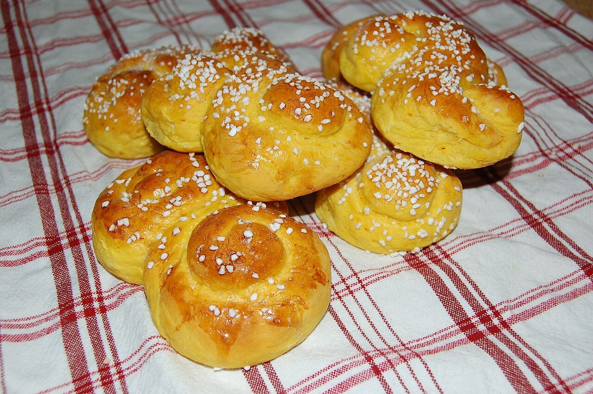 Lussekatter med pärlsocker på en rödrutig bakduk