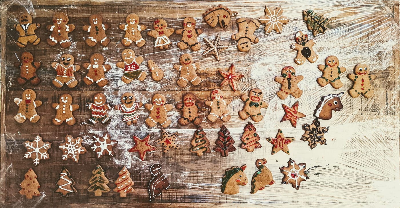 Díszített mézeskalács figurák, csillagok és fenyőfák egy asztalon
