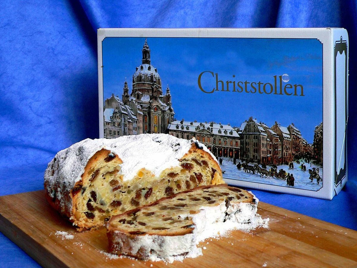 Aufgeschnittener Christstollen mit Puderzucker vor einer Stollenschachtel